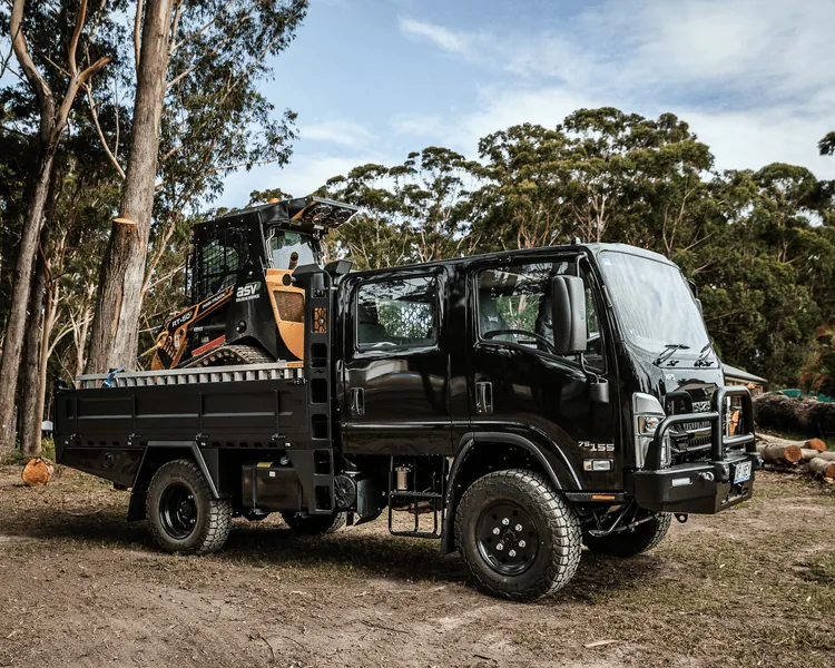 Black Isuzu NPS tipper body truck with excavator in forest work site